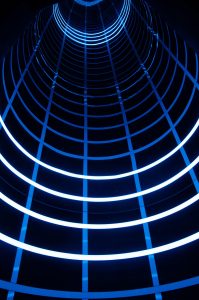Blue-lit tunnel with geometric light patterns, used to represent experimental motion and immersive spatial interaction.